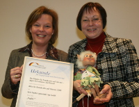 Papiliogründerin Heidrun Mayer (links) hält eine Urkunde, Bundestagsabgeordnete Gabriele Fograscher (rechts) die Marionette Freudibold in den Händen.