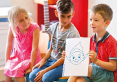 Drei Grundschulkinder mit Freudibold-Zeichnung
